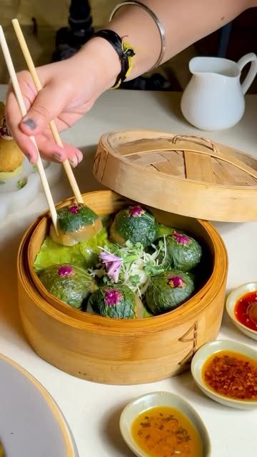 Spinach dumplings in a bamboo basket with dips