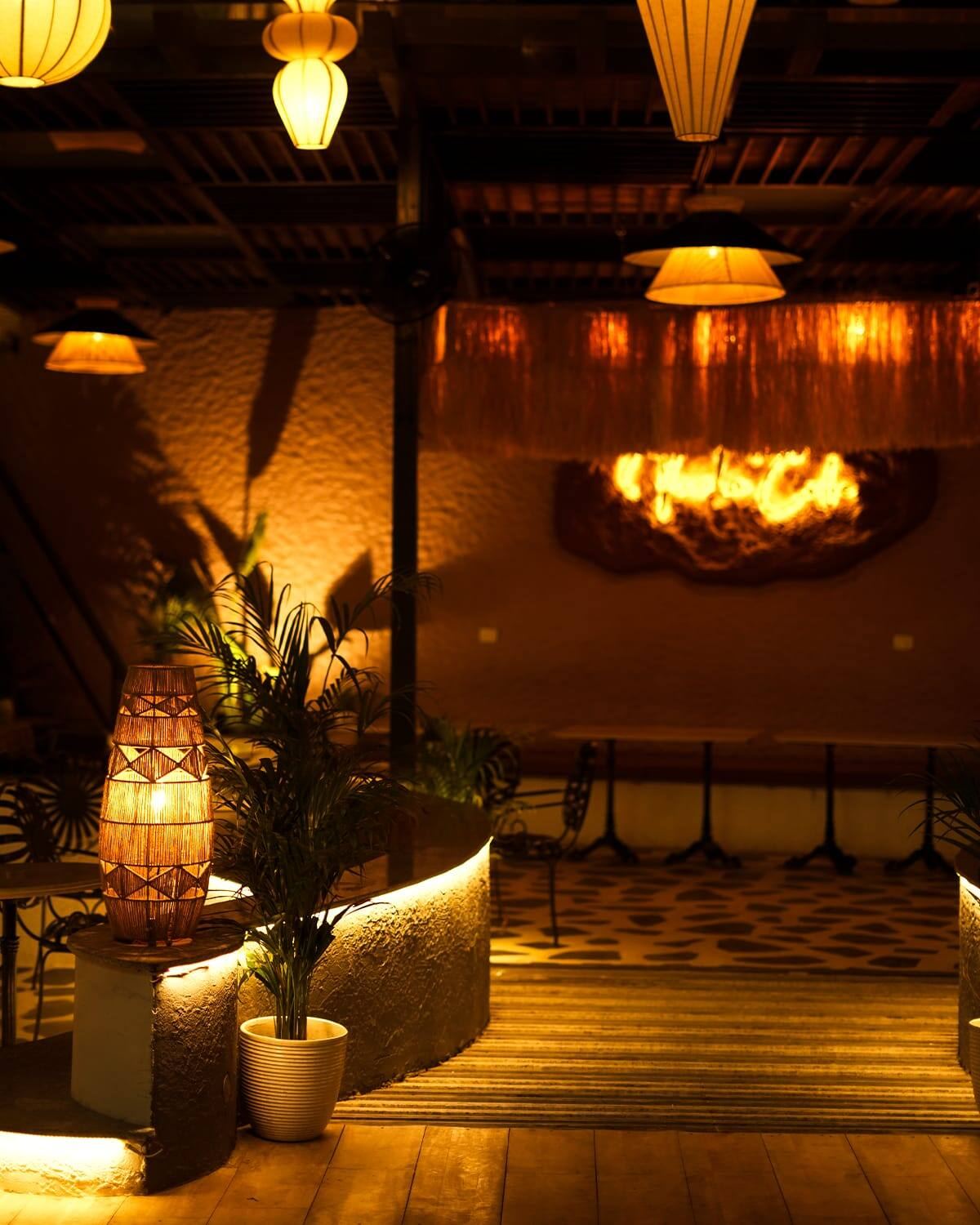 Vicolo's lantern-lit courtyard at night, rattan lamps glowing over the seating