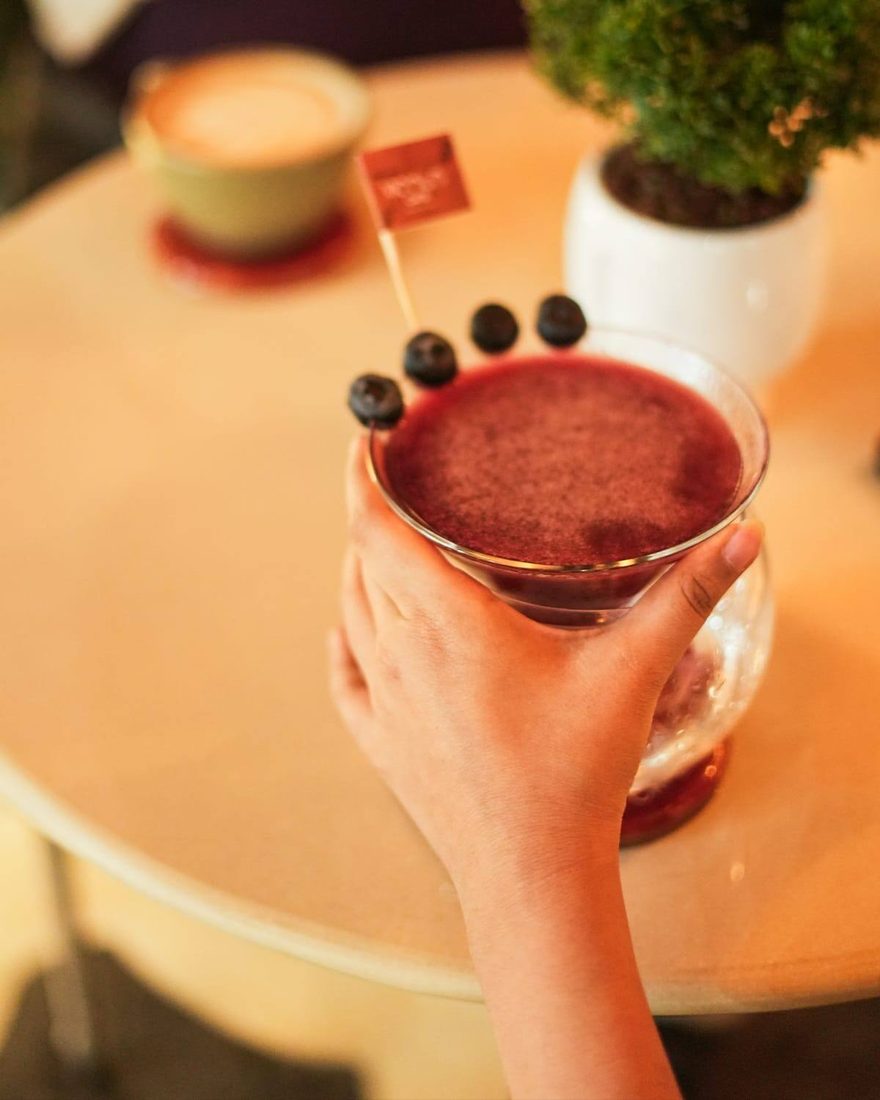 A berry mocktail held over a cafe table